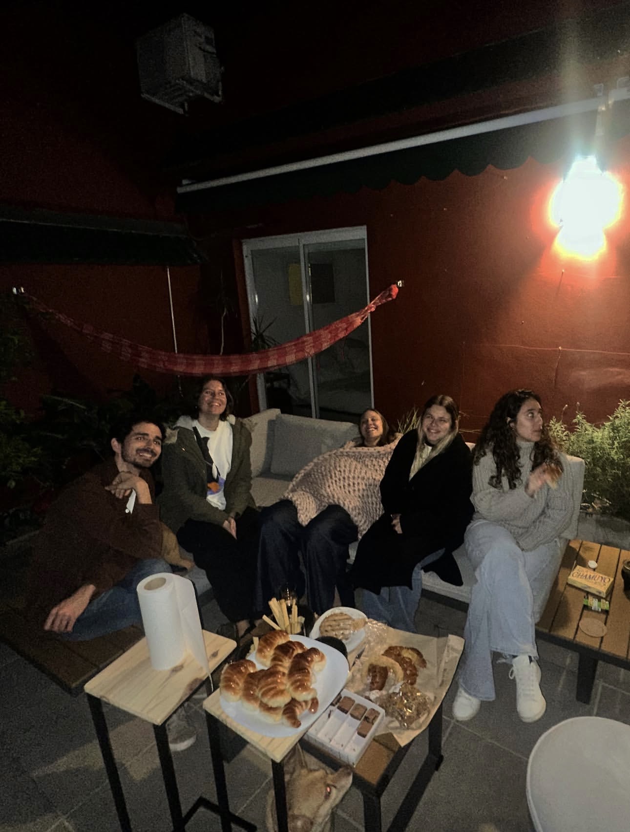 Friends relaxing on a patio at night with pastries