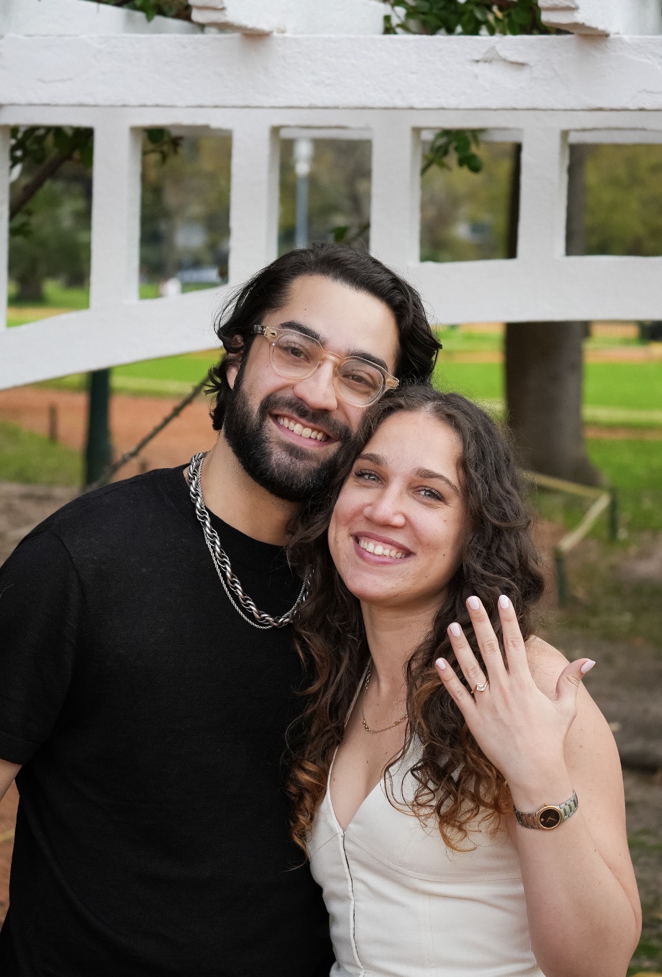 Mica and Alex smiling together in a Buenos Aires garden, showing her engagement ring