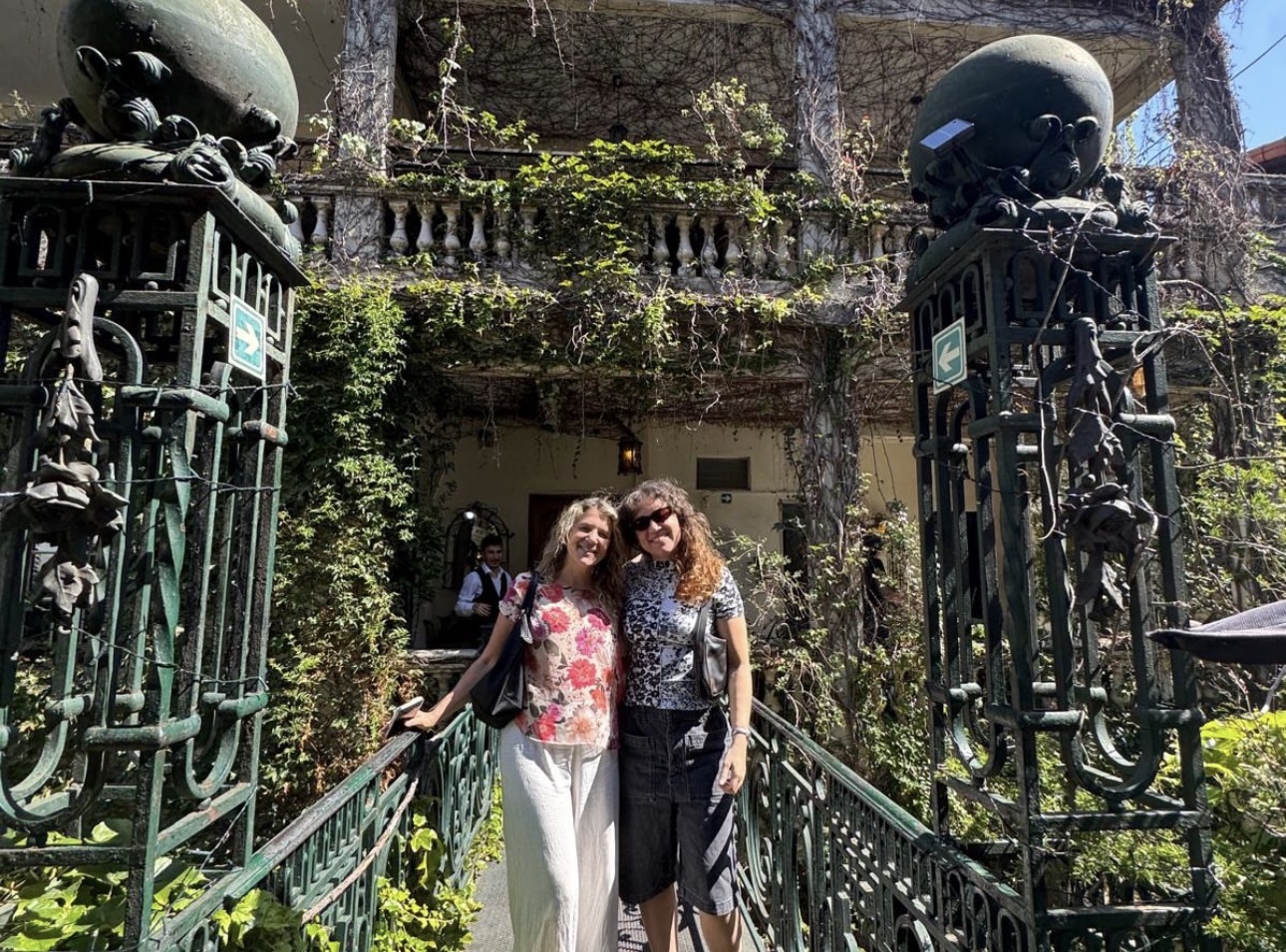 Two guests smiling at an ornate garden gate in Buenos Aires